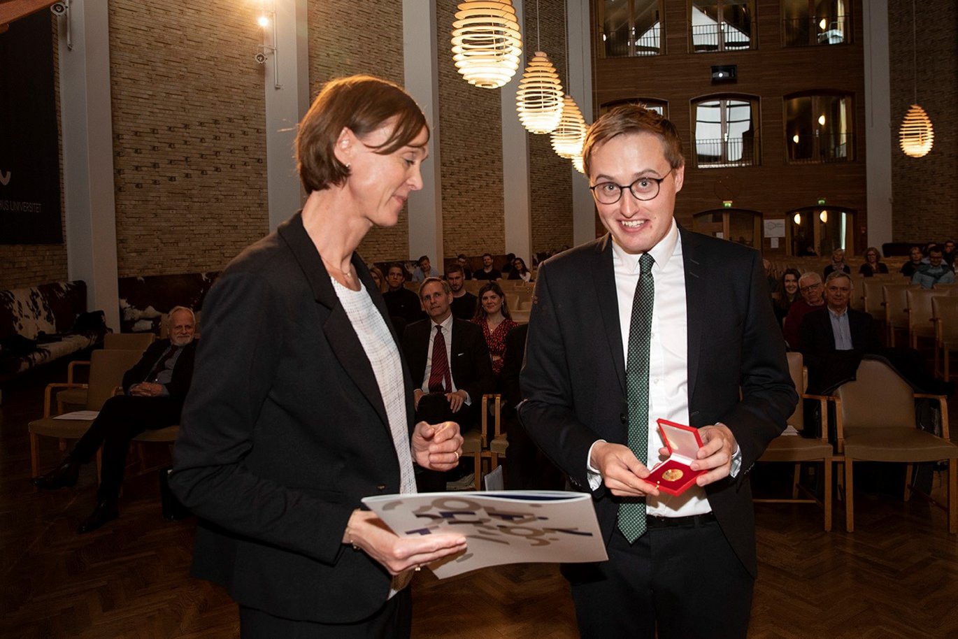 Andreas modtager her sin guldmedalje, som overrækkes af professor ved Juridisk Institut på Aarhus BSS, Hanne Søndergaard Birkmose. Foto: Lars Kruse